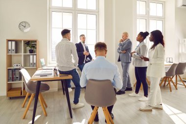 Muhtelif iş grupları ofiste beyin fırtınası yapıyor. Mutlu çok ırklı meslektaşlar, iş arkadaşları projeyi tartışıyor, fikirleri paylaşıyor, beyin fırtınası yapıyor. Erkek akıl hocası danışmanı, çalışanlarla konuşuyor.