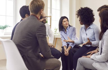 Çok kültürlü iş adamlarından oluşan bir grup bir daire içinde oturuyorlar, yakın plan. Afrikalı Amerikalı çalışanlar takımla konuşuyor. İnsan kaynaklarını, işadamını, boş vakitleri kavramsallaştır.