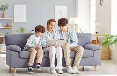 Anne ve oğulları boş zamanlarını evde birlikte geçiriyorlar, kanepede oturup, bir aile fotoğrafı albümüne bakıyorlar. Bu mutlu an aile bağlarını, hatıraları ve birlikteliği yakalar..