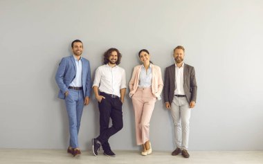 Aşırı mutlu başarılı çok ırklı iş adamlarının portresi gri duvarın karşısında birlik liderliğini gösteriyor. Gülümsemek, ofisteki çeşitli meslektaşları motive etti. İş ekibi, takım çalışması konsepti.