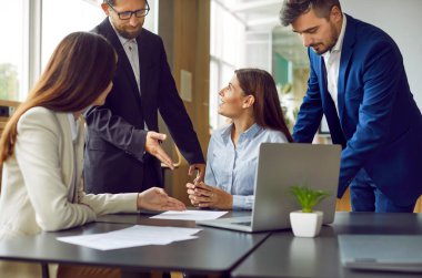 Genç iş adamlarından oluşan bir ekip ofis masasında toplanıyor. Erkek ve kadın çalışanlardan oluşan bir grup güncel meseleleri tartışıyor, bazı belgelere bakıyor ve dizüstü bilgisayar kullanıyor.