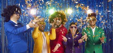 Mutlu insanlar parlak mavi arka planda düşen konfetileri yakalıyor. Renkli parti takımları, gözlükler ve gece kulübünde eğlenen komik kıvırcık peruklar giyen bir grup arkadaş. Gece hayatı ve disko konsepti