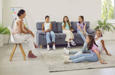 Dost canlısı genç psikolog bir grup genç kızla sohbet ediyor. İlkokul öğrencileri bayan öğretmenleriyle oturup akıl sağlığı dersi alıyorlar..