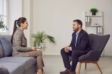 Bir kadın gazeteci gülümseyen bir iş adamıyla kurumsal bir röportaj yapıyor. Basın için bilgi edinme kavramı. Bir şirketin veya iş ortamının medya ile etkileşimi