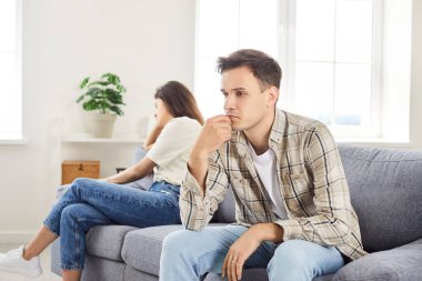 Evdeki kanepede oturan ve birbirlerine sırt çeviren genç bir çifti gücendirdi. Bir erkek ve bir kadın bir kavga yüzünden üzgün. Kavram sorunları, çatışma çifti krizi