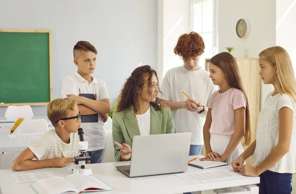 Ciddi okul fen bilgisi öğretmeni bir grup çocuk öğrenciyle iletişim kurar, güvenilir bilgilerin nasıl aranacağı ve yazılacağı konusunda tavsiyelerde bulunur, hataları düzeltir ve sınav sınavına hazırlanır