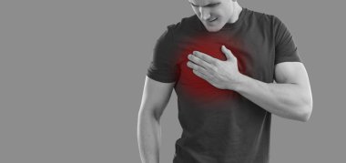 Genç adamın göğsünün sağ tarafında gri arka planda dururken yanma belirtileri var. Göğsünün sağ tarafında kırmızıyla işaretlenmiş hassas noktaya tutunan adamın siyah ve beyaz görüntüsü..