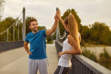 Aktif genç çift sabahları dışarıda idmandan sonra birbirlerine beşlik çakıyor. Kafkas sporcu ailesi birbirlerine destek ve birlik gösteriyorlar. Spor, spor, açık hava sporu konsepti.