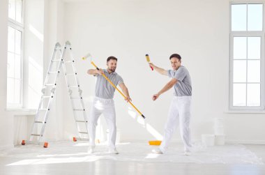 Profesyonel boyacı ekibi ellerinde boya rulosu tutuyorlar ve yeni dairenin duvarını boyarken eğleniyorlar. Tamirat yapan müteahhitler taşınmaya hazırlanıyor. Konsept yenileniyor.