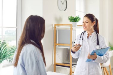 Female doctor or nurse engaged in a conversation with a patient during a medical consultation in the hospital. Focusing on healthcare, medicine, and patient care within the clinic setting.