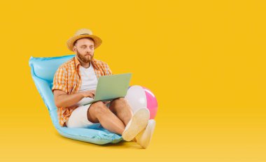 Happy man in beach holiday wear laptop working sitting on summer inflatable mattress, rubber ball. Leisure, recreation, travelling, happy to work remote outside of corporate office, enjoy freelancing