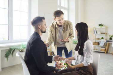 Scene of romantic proposal turning into dramatic confrontation with rival standing upset while couple shares tender moment. Love triangle tension shows jealousy, rivalry and strong emotions.