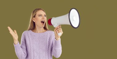 Screaming in megaphone. Beautiful young woman using loudspeaker announces special offer, shopping time, protest or meeting. Woman speaks into megaphone on khaki background. Web banner.