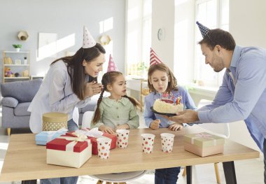 Happy birthday candle cake blowing celebration, friendly family portrait, parents, kids party together for special event, smiling people gathering making fun, enjoy time, wishing great happiness, joy