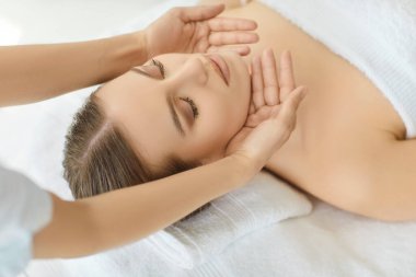 Beautician hands massaging woman face, female client lying relaxing with eyes closed in spa saloon cosmetologist cabinet, gently applying, calm tranquil atmosphere for beauty treatment receiving 