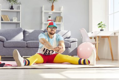 Funny man in colorful sportswear performs stretching exercises during home fitness routine. Workout includes a variety of training activities, making the sport session in home gym both effective.