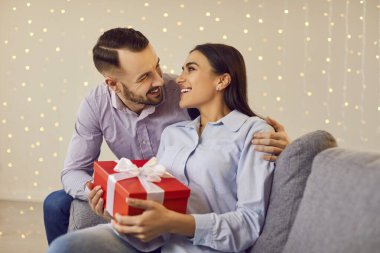 Happy people in love close holding red gift box, enjoy special romantic moment. Valentine day emotion, loving male, female pair, family couple celebrate romance, enjoy intimacy, wall garland design