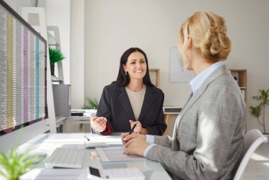 Happy female coworkers working together in office during meeting, using computer for business accounting in conference, focusing on teamwork in a professional surroundings with collaboration.