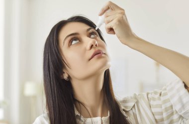Young woman using medical eyes drops at home, dry eyes syndrome or curing ophthalmology disease, eyesight care, treating eyes, liquid medications to relieve dryness and irritation, soothing relief 