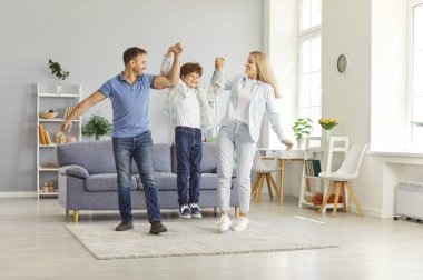 Happy friendly family fun, playful funny parents, child having joy together with little son in modern living room, dad and mother with cute boy doing exercises, enjoying holiday, weekend at home