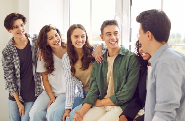 Fostering unity and collaboration, a diverse group of teenage students together engages in lively conversations in a school classroom. Witness the exchange of ideas and the sense of people community.