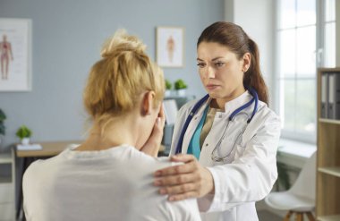 Portrait of female doctor therapist supporting his female sick upset crying patient in office. Physician standing in medical clinic giving consultation a woman during examination. Medicine concept.