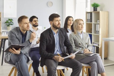 Attentive and focused business people join team meeting or conference in the office, presentation and teamwork, emphasizing community and group effort in a bustling work environment.