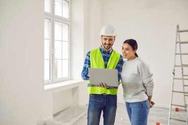 Foreman and female apartment owner discussing house design plan at home. Professional civil engineer showing blueprint of renovation of house to young woman indoors. Building and home renovation
