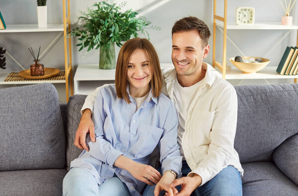 Home portrait of happy young married couple in love posing for photo seated on couch in modern living room, apartments, enjoy harmonic relationships, care and sincere feelings, loving people 