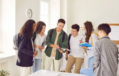 Diverse group of teenage students at school classroom engages in conversations. Smiles reflect the joy of shared moments, fostering communication and building connections among the school community.