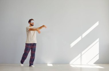 Uyurgezer, pijamalı bir adam. Uyku bozukluğu olan uykulu bir adam boş bir odada gözleri kapalı yürüyor. Pijamalı ve maskeli bir adam uykulu zombi yürüyüşüyle yürüyor.