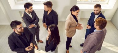 People communicating at a work meeting or business event. Group of young men and women talking while standing in the office. Business, communication concept. Banner. Shot from above