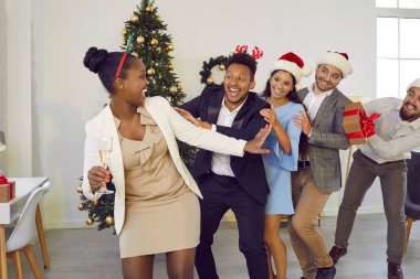 Dancing, running in row, having fun multiracial happy cheerful friends at Christmas party. Men and women celebrating New Year winter holidays, drinking alcohol. Friendship, long life friends concept.