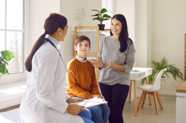 Portrait of a little boy patient with his happy smiling mother talking with paediatrician doctor on consultation in clinic and listening the recommendations after medical examination.