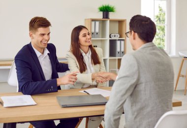 Mutlu çift sözleşme imzalıyor ve simsar ya da sigortacıyla el sıkışıyor. Genç bir adam ve kadın, yatırım danışmanlarıyla iyi bir anlaşma yapıyor..