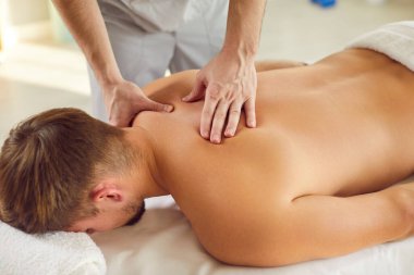 Close up of a hands of a masseur and physiotherapist performing a back massage or spa treatment on a patient lying in a clinic or salon. Release tension and relaxation through stretching techniques.