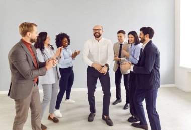 Smiling businessman dancing with team of business colleagues, celebrating success during a corporate event in the office. The group enjoys a lively party, highlighting achievements.