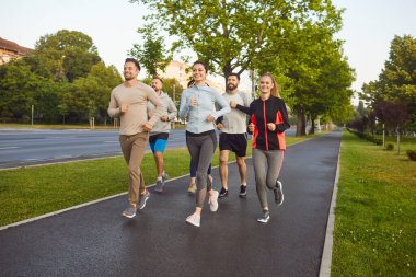 Team of athletes runs or jogs together outdoors during group training, boosting jogging effort, enhancing sport workout, uniting in running activity, engaging in a dynamic open fitness space.