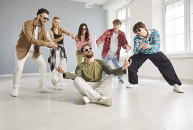 Cool dancer man, group of dancing people actively dancing indoors, moving and posing in studio space, dance class, rehearsal in dynamic pose, enjoying practicing or performing, having fun together