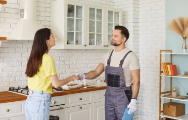 Handshake of plumber and customer at home kitchen, woman greeting professional repairman to repair sink, fix plumbing. Satisfied client and handyman shake hands. Maintenance service, good work concept
