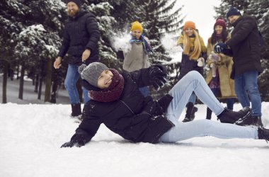 Smiling friends in outerwear laugh relaxing together outside playing snowballs in snowy forest on weekend. Happy young people have fun enjoy winter vacation or holiday in park. Snow recreation.