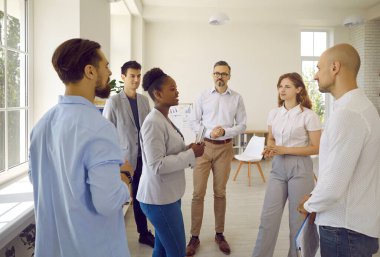 Group of scientists from different countries communicate during break in scientific symposium with supervisor. African American woman convinces colleagues of correctness of scientific conclusions.