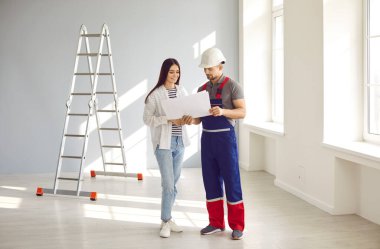 Foreman and home owner discussing house design construction plan. Professional builder, working man in hardhat and female customer looking at blueprint of renovation and interior decoration