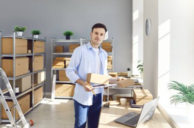 Portrait of a man working in an online store warehouse, conducting inventory of parcels. Focus and dedication to managing storage and packages efficiently in an online retail environment.