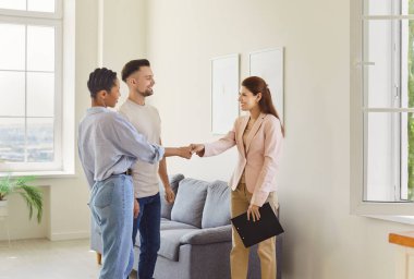 Real estate agent, female realtor meets client couple to deal, show, present new property, shaking hands smiling welcoming for mutual agreement, contract, successful transaction, moving modern home 