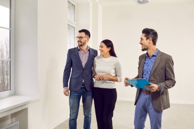 Pencereden manzaraya bakan genç ve mutlu bir çifte ev gösteren bir emlakçı. Profesyonel emlakçı yeni bir daire gösterdi. Aile ev sahibi olmaya hazır. Emlak piyasası kavramı.