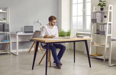 Ofiste dizüstü bilgisayarla çalışan, monitör ekranına bakıp hesaplamalar yapan, yeni projeleri değerlendiren, şirketi analiz eden ciddi ve çekici bir iş adamının portresi..