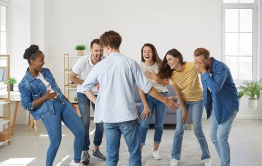 Multiracial friends meet up, enjoy free time and have fun together. Group of happy cheerful young diverse mixed race people laughing at a very good funny joke all together