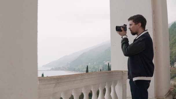 Jonge fotograaf foto's neemt op een camera, hij is in de natuur in het interieur — Stockvideo