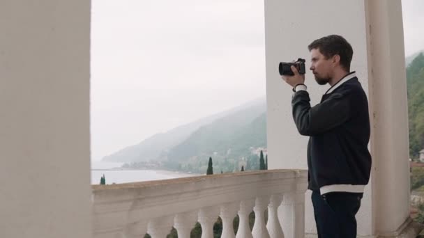 Jeune photographe prend des photos sur un appareil photo, il est dans la nature à l'intérieur — Video